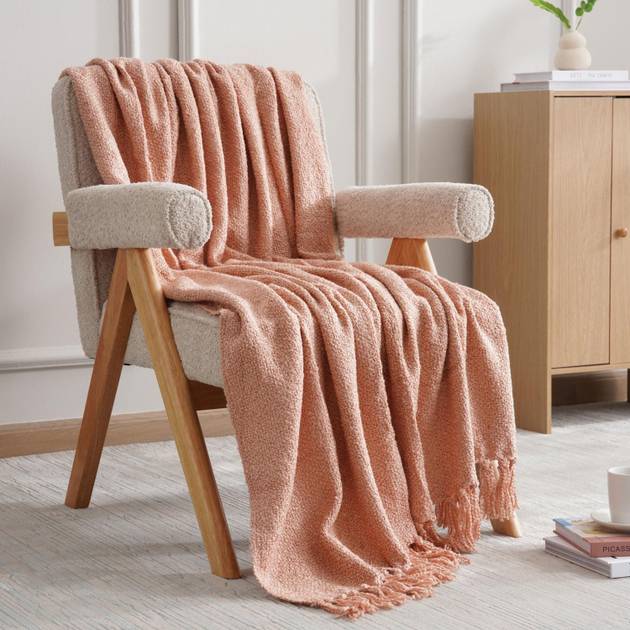 Pink blanket draped over a chair in a room with a wooden cabinet and books.