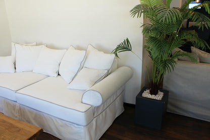 White sofa with white cushions in a living room setting with a plant. Venice Collection Sofa – Deep Comfort for Modern Living | Vella Concept