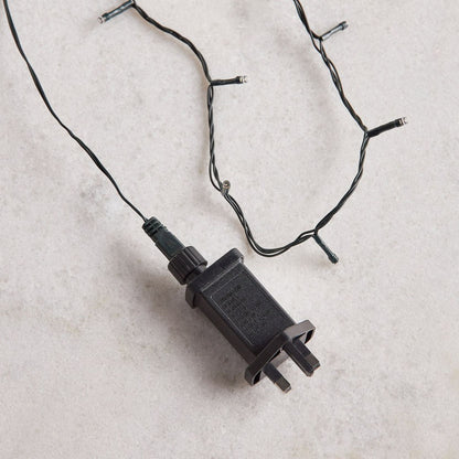 Black electrical plug on a light string against a light background