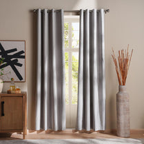 Striped curtains hanging in a room with a vase and abstract art on the wall.