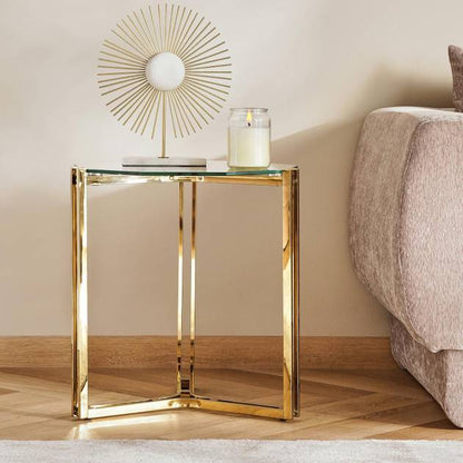 Gold side table with a candle and decorative mirror in a room setting.