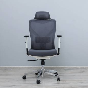 Gray office chair with headrest on a wooden floor against a gray wall