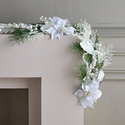 Decorative garland with white flowers and greenery on a fireplace mantel.