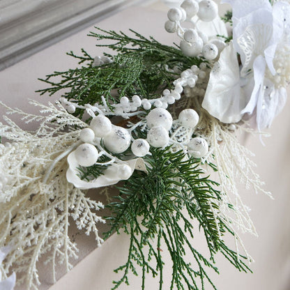Decorative garland with greenery, white berries, and shells on a neutral background