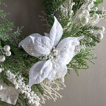 Decorative wreath with white flowers and greenery on a neutral background