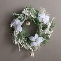 Decorative wreath with greenery, white flowers, and gold ornaments on a plain background