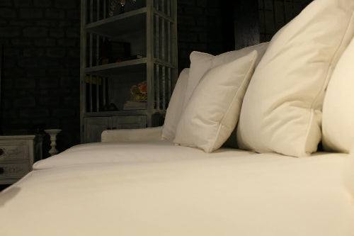 White pillows on a bed in a dimly lit room - Bodrum Collection Sofa – Elegance Meets Everyday Comfort | Vella Concept