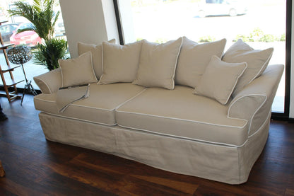 Beige sofa with cushions in a room with large windows and plants. Bosphorus Collection Sofa – Minimalist Elegance for Modern Homes | Vella Concept