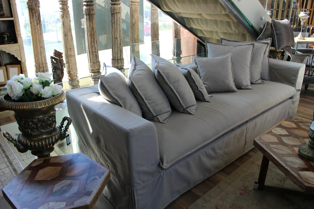 Gray sofa with decorative pillows in a room with large windows and architectural columns. Cappadocia Collection Sofa – Simple, Serene & Timeless | Vella Concept