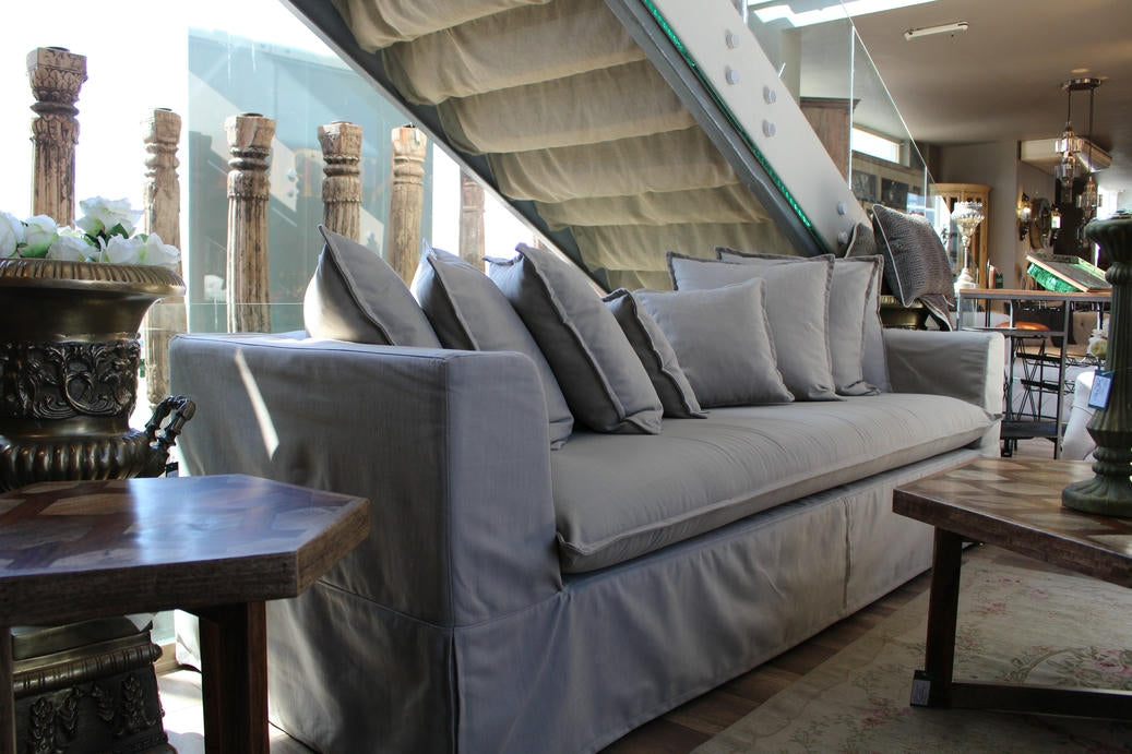 Gray sofa with decorative pillows in a room with a staircase and decorative elements. Cappadocia Collection Sofa – Simple, Serene & Timeless | Vella Concept