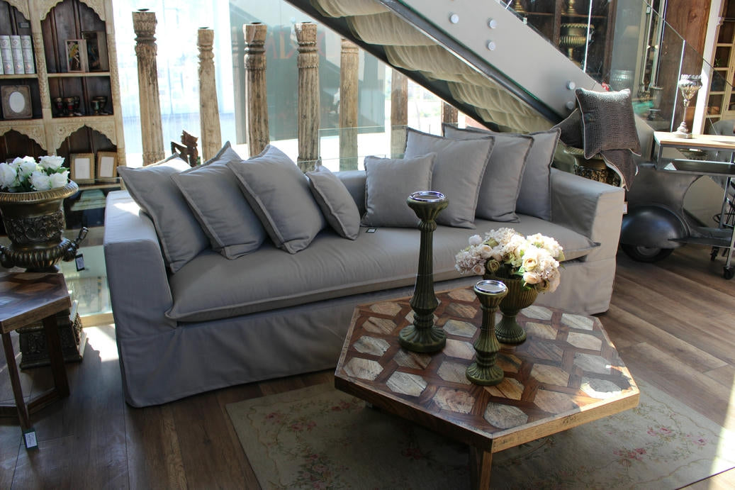 Gray sofa with decorative pillows in a room with wooden flooring and a stone coffee table. Cappadocia Collection Sofa – Simple, Serene & Timeless | Vella Concept