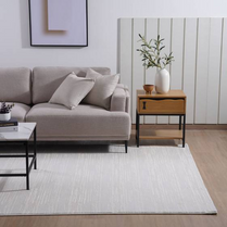 Modern living room with a gray sofa, wooden side table, and white rug.