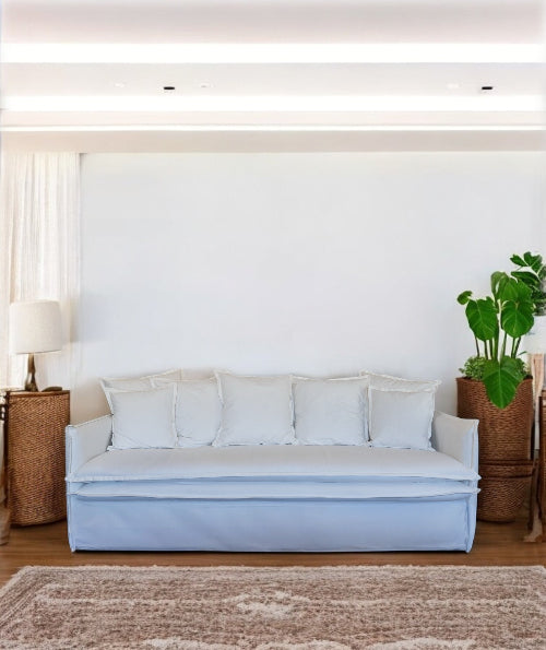 Light blue sofa in a living room with a white wall, plant, and side table. Istanbul Collection Sofa – Minimal Touch, Maximum Comfort | Vella Concept