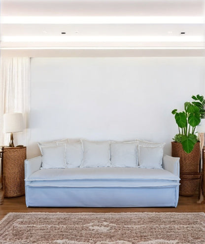 Light blue sofa in a living room with a white wall, plant, and side table. Istanbul Collection Sofa – Minimal Touch, Maximum Comfort | Vella Concept