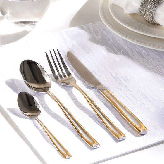 Set of gold and silver flatware on a white tablecloth