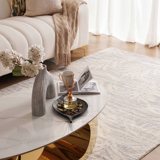 Living room with a coffee table, vase, and books on a rug