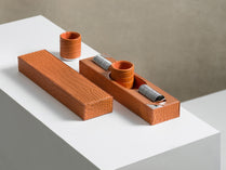 A set of brown backgammon checkers with metal detailing placed on a white surface.