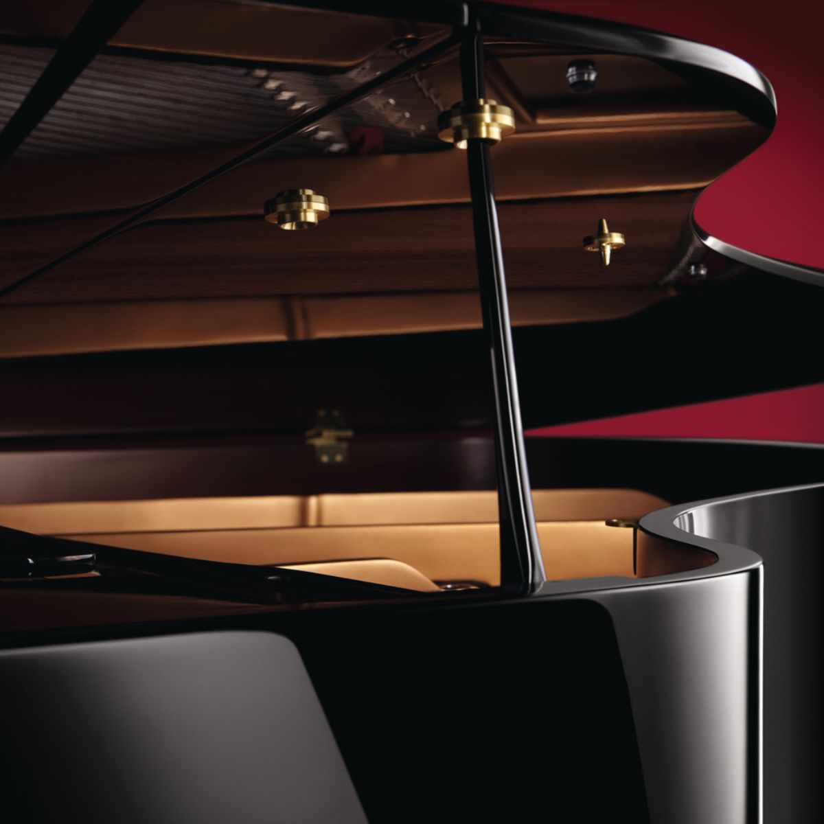 Close-up view of a black and white grand piano with the lid open, showing the inner mechanism and part of the keyboard.