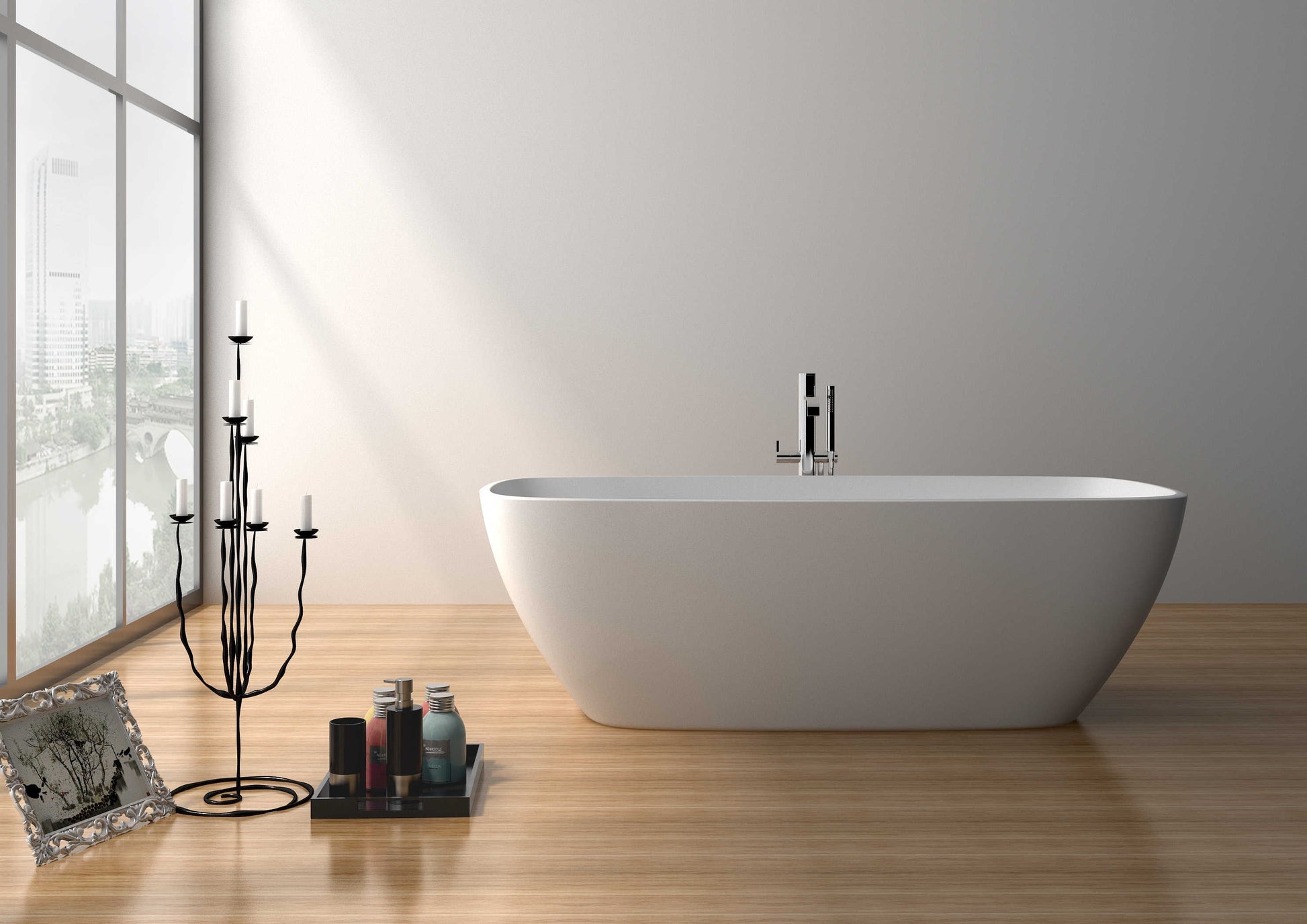 A white freestanding bathtub positioned on a wooden floor, with a window in the background and a black candle holder and bottles beside the tub.